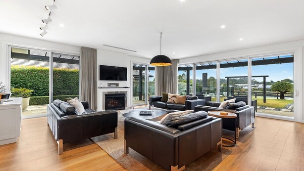 A spacious living room with a fireplace, comfortable seating, and large windows offering a view of the outdoors.