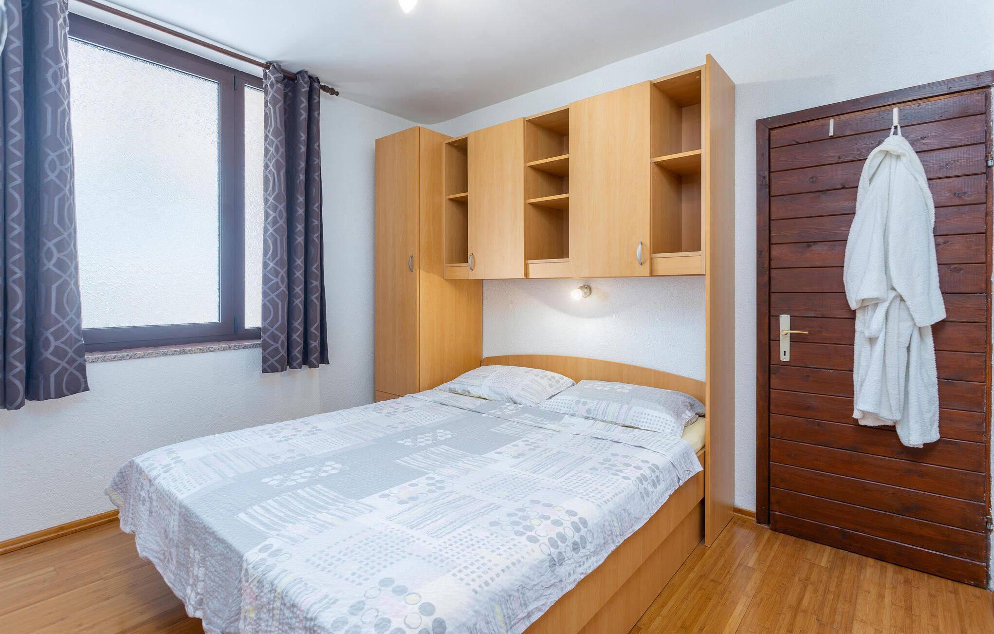 A bedroom with a bed, wooden wardrobe, and a door with a towel hanging.