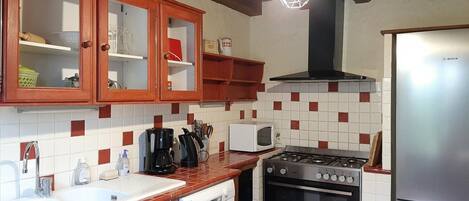 Una cocina con armarios de madera, estufa, microondas y refrigerador Bosch.