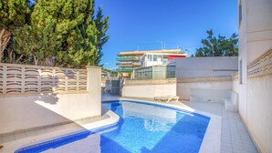 A swimming pool with a tiled edge, surrounded by a low wall and a fence with a decorative pattern. - Cozy apartment in El Campello with WiFi (El Campello)