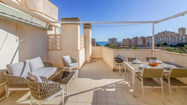 A balcony with a view of the sea, furnished with wicker chairs and a table set for dining. - Cozy apartment in El Campello with WiFi (El Campello)