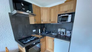 A compact kitchen with wooden cabinets, a microwave, a coffee maker, and a built-in oven. - Studio with Balcony near Bossonnet, La Clusaz - Sleeps 4 with Garage (La Clusaz)