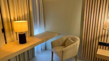 Una habitación moderna con un escritorio de madera, una silla acolchada y una lámpara.