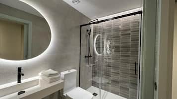 A modern bathroom with a glass-enclosed shower, a white sink, and a toilet.
