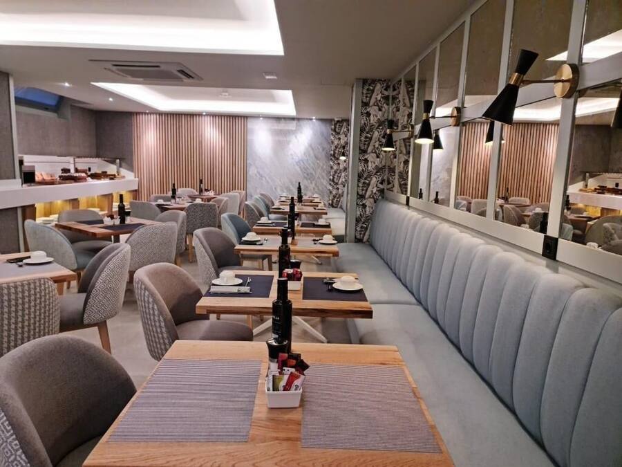 Un restaurante moderno con cabinas y mesas, una barra alargada y una pared con diseño.