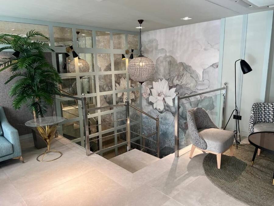 A modern interior with a staircase, a glass partition, a large potted plant, and contemporary furniture.