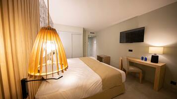 Ein Hotelzimmer mit einem Bett, einem Schreibtisch, einem Stuhl, einem Fernseher und einer Lampe.