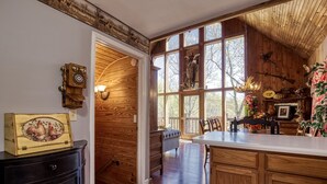 A rustic kitchen with wooden walls, a large window with a view of trees, and a dining area with a wooden table and chairs. - Close to town with private Mountain Setting 3 Bedroom 3 Bathrooom Pet Friendly  Hot tub (Sevierville)