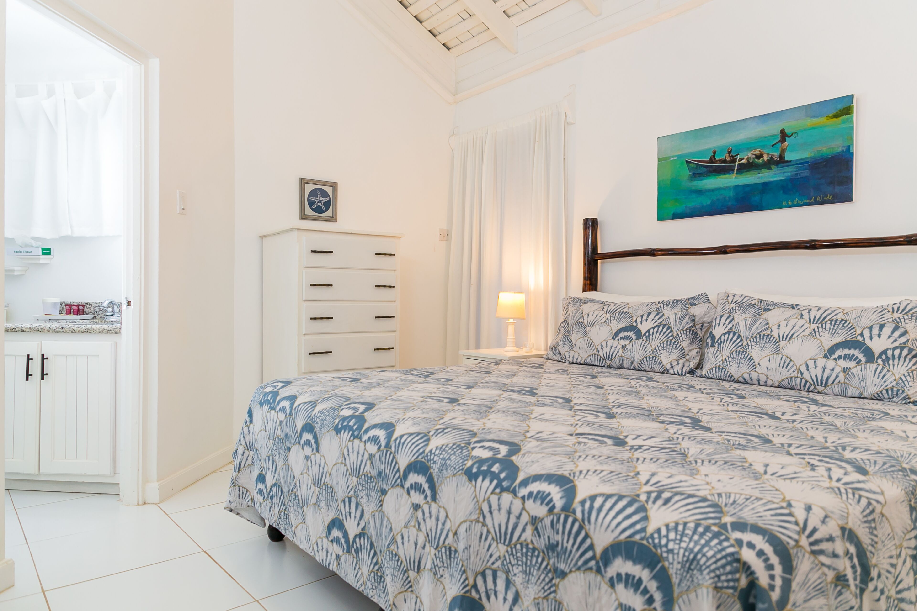 A bedroom with a bed, a nightstand, a dresser, and a painting on the wall.