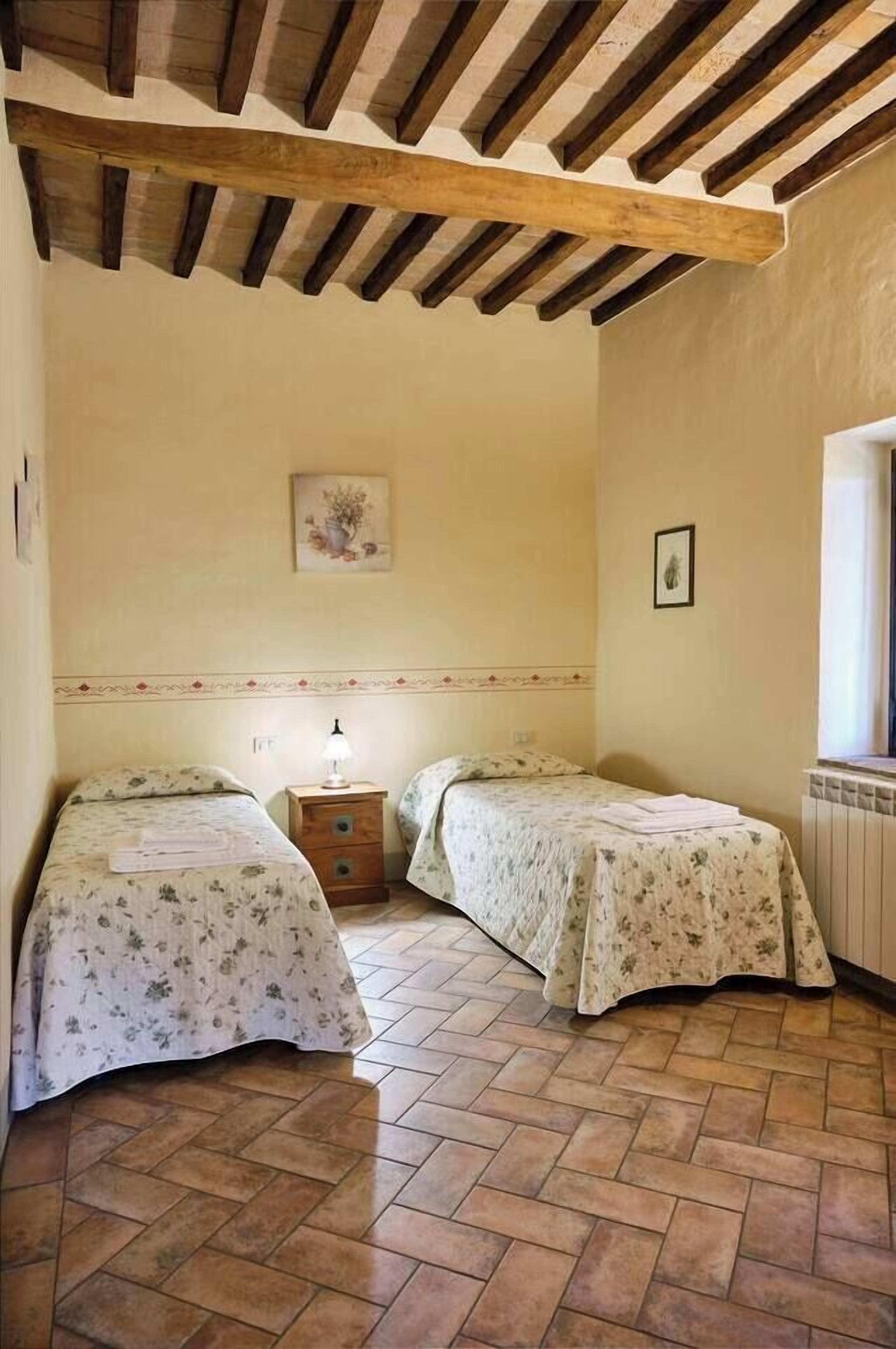 Une chambre avec deux lits simples, un plafond en bois, un radiateur et une fenêtre.
