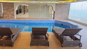 An indoor swimming pool with a tiled edge, surrounded by wicker lounge chairs. - Sumou Hotel Al Khobar (Al Khobar)