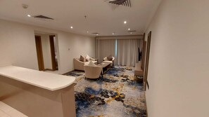 A hotel room with a reception desk, a sofa, a chair, and a patterned carpet. - Sumou Hotel Al Khobar (Al Khobar)