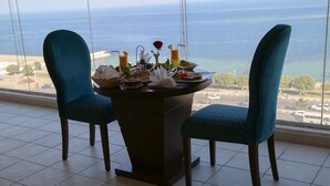 A dining table with chairs and a view of the ocean. - Sumou Hotel Al Khobar (Al Khobar)