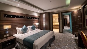 A modern hotel room with a large bed, a nightstand with a lamp, and a view of the bathroom through an open door. - Sumou Hotel Al Khobar (Al Khobar)