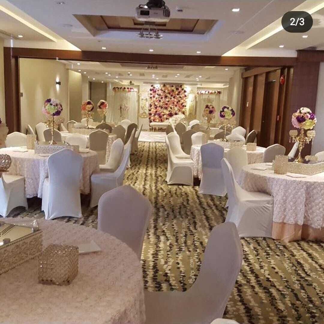 A banquet hall with round tables, white chairs, and floral centerpieces.