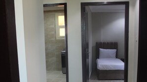 A hallway leading to a bedroom with a bed and a bathroom visible in the background. - ماجيك سويت الرقعى Magic Suite ALRaggi (Kuwait City)