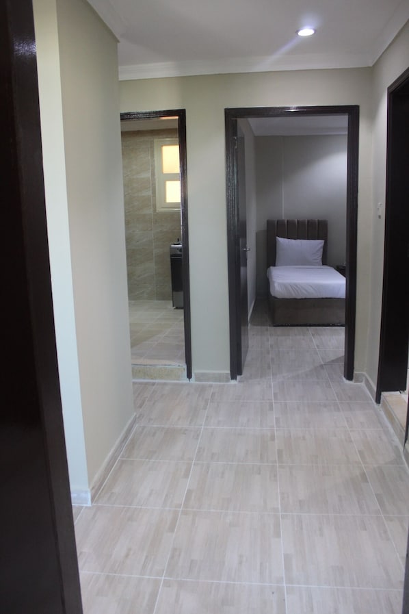 A hallway leading to a bedroom with a bed and a bathroom visible in the background. - ماجيك سويت الرقعى Magic Suite ALRaggi (Kuwait City)