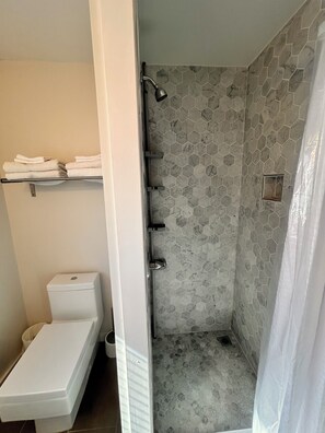 A bathroom with a shower, toilet, and towel rack.