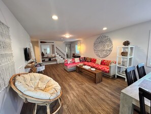 A living room with a sofa, coffee table, and a chair. There is a staircase leading to another room. - New 4 BR PRIME Location 1 block to Casino Pier! Front Unit of two unit house. (Seaside Heights)