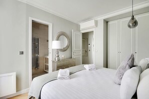 A bedroom with a bed, a dresser, a mirror, and a door leading to a bathroom.