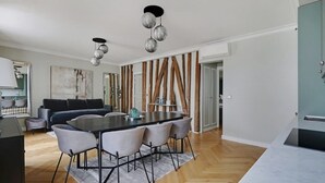 A modern kitchen with a marble countertop, a dining table with chairs, and a hanging light fixture. - Rue Lepic - quintessential winding cobblestone street- Take a step into the past (Paris)