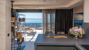 A modern kitchen with a view of the sea, a dining area with a table and chairs, and a decorative vase on the counter. - villa Aurelia 2-amazing sea and city rooftop view (Makarska)