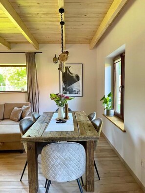 A dining area with a wooden table, chairs, and a hanging light fixture.
