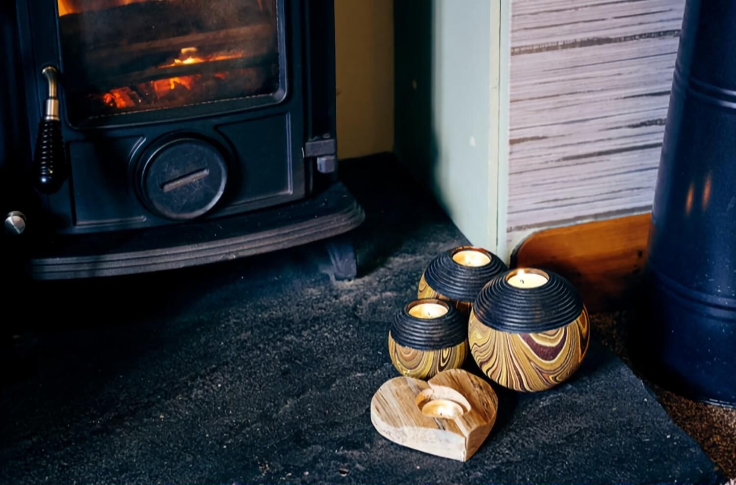 A wood-burning stove with three decorative candle holders in front of it.