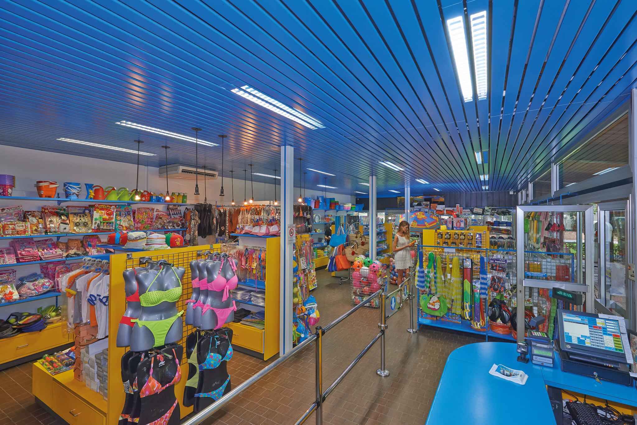 Ein hell erleuchteter Laden mit bunten Waren auf Regalen und Kleiderstangen, darunter Kleidung und Accessoires.