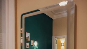 Ein Schlafzimmer mit einem Bett, einem Nachttisch, einer Lampe und gerahmten Bildern an der Wand.