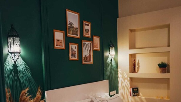Ein Schlafzimmer mit einem weißen Bett, zwei Nachttischen, einem Wandregal und zwei Wandleuchten.