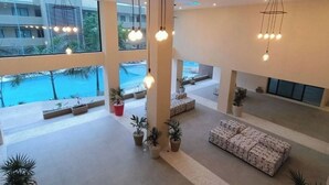 En rymlig lobby med stora fönster, utsikt över poolen och modern belysning.