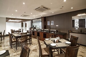 Un comedor con una mesa larga y sillas, un mostrador de buffet y un espejo grande en la pared.