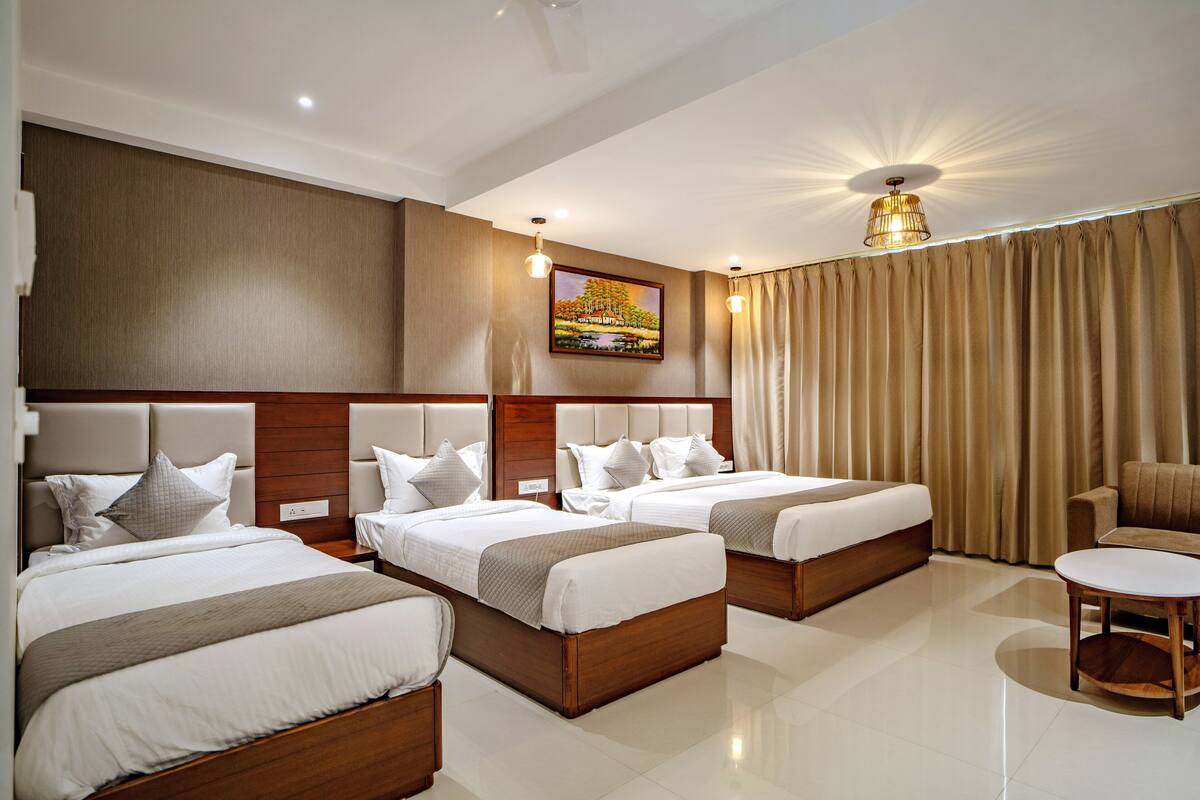 A hotel room with two beds, a sofa, a small table, and a painting on the wall.