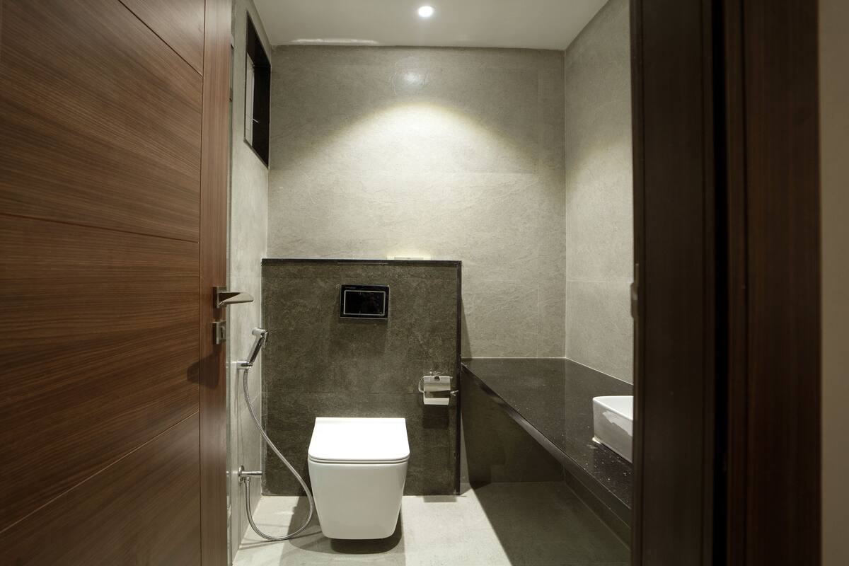A modern bathroom with a wooden vanity, a white toilet, and a shower area.