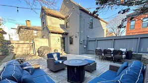 Un patio à l’arrière de la maison, avec des meubles d’extérieur, un barbecue et une zone de patio couverte.