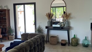 A living room with a large sofa, a coffee table, a mirror, and a bookshelf. - Villa Avec Piscine (Porto-Vecchio)