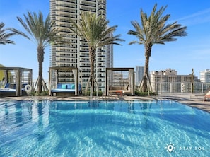 A rooftop pool with lounge chairs and palm trees, surrounded by high-rise buildings. - Ocean View Balcony|Beachfront Resort+Amazing Pools (Hollywood)
