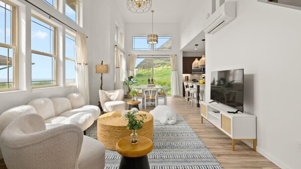 Amplia sala de estar con un sofá, una mesa de centro y un televisor. Cuenta con ventanas grandes y vistas al exterior.