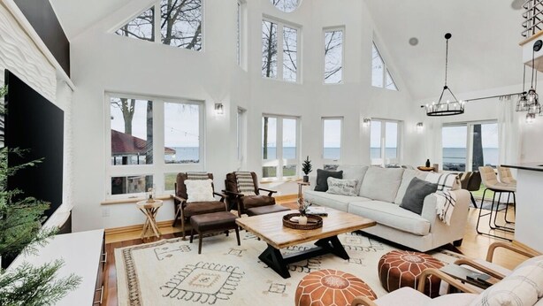 Ein geräumiges Wohnzimmer mit großem Meerblick, einem Kamin und einer modernen Deckenleuchte.