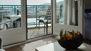 Un balcón con mesa y sillas, vista al mar y un comedor con mesa y sillas.