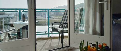 Uma varanda com mesa e cadeiras, vista para o mar, e um espaço de refeições com mesa e cadeiras.