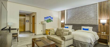 Una habitación de hotel con cama, sofá, escritorio y televisión.