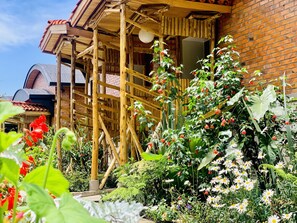 A wooden structure with a brick wall and a garden with various plants and flowers. - Virunga Inn Resort & SPA (Musanze)