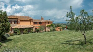 A large house with a tiled roof, surrounded by a well-maintained lawn and trees.