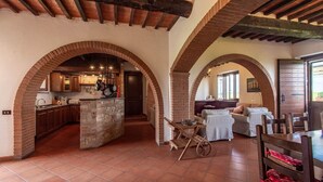A rustic interior with brick arches, a kitchen, and a seating area with a view.