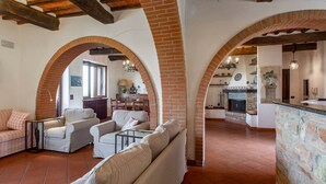 A spacious living area with a fireplace, arched brick walls, and a cozy seating arrangement.