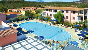 Un espace piscine offrant une vue dégagée sur les bâtiments environnants, une terrasse carrelée et un paysage montagneux en toile de fond.