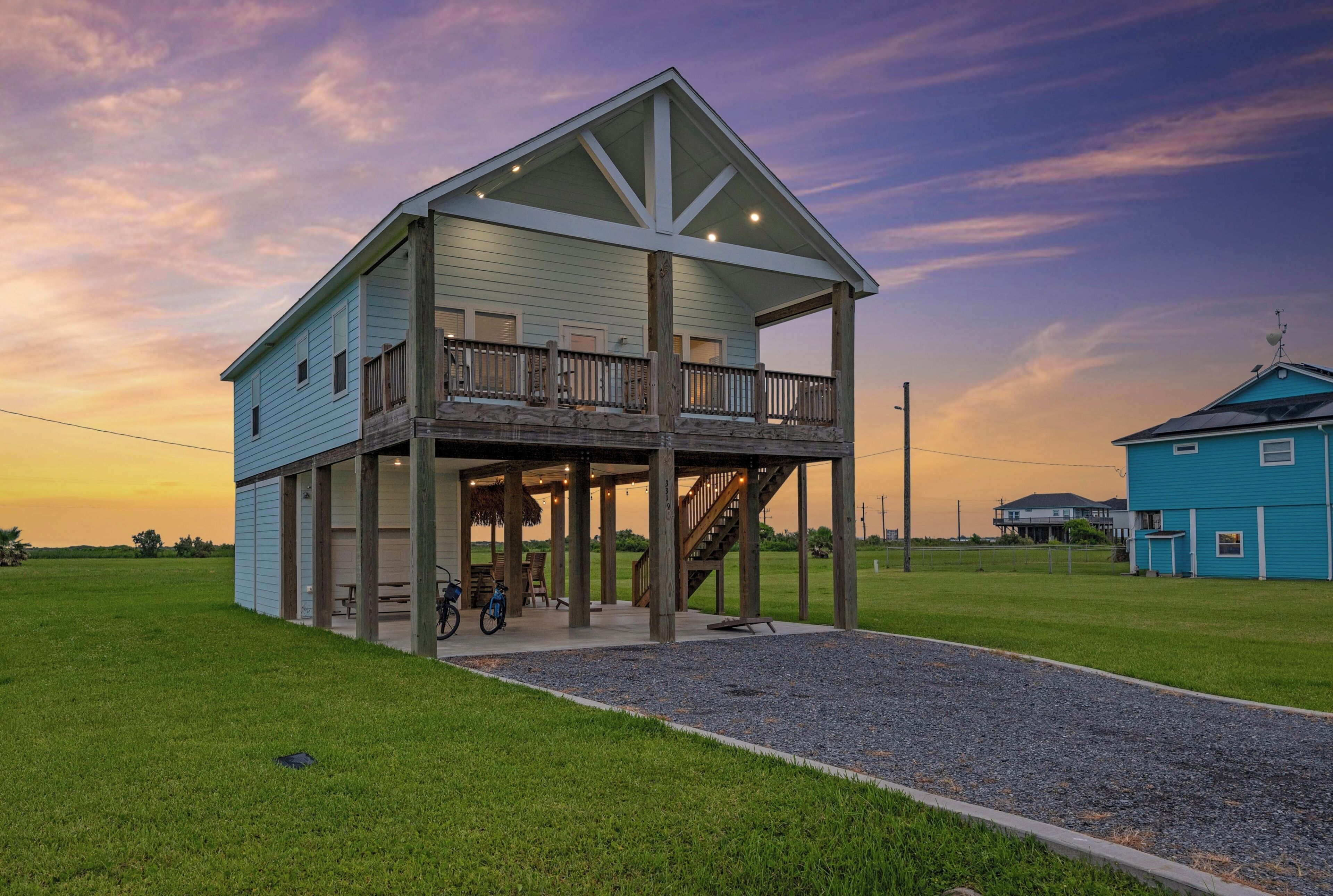 A two-story house with a balcony, a covered porch, and a gravel driveway.
