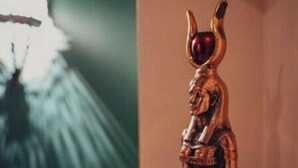 A statue of a figure with a headdress and a red gem, standing in a room with a green wall and a light fixture. - Cozy 1 bedroom Queen 2 (Cairo Governorate)